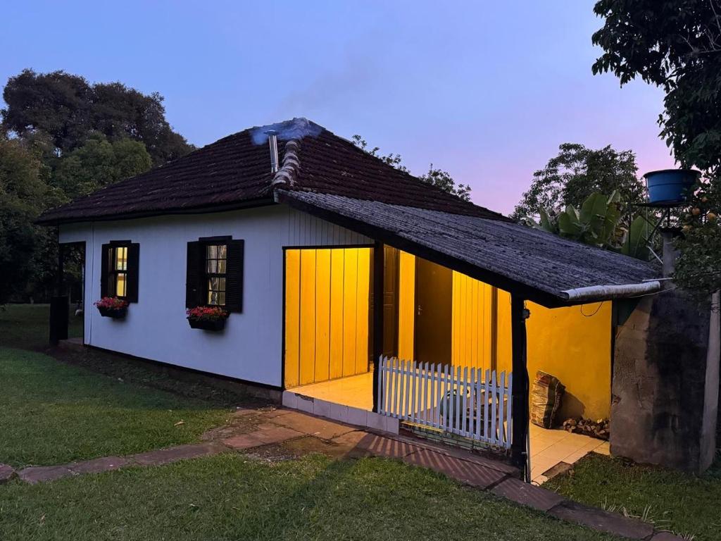 a small house with yellow doors and a fence at Casa Centenária com 20 min de Gramado in Três Coroas