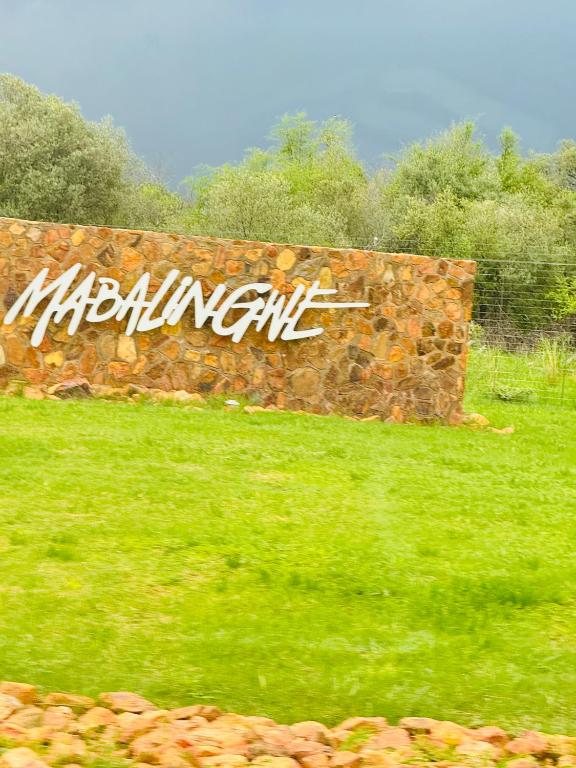 a stone wall with graffiti on it in a field at Mabalingwe Mistykie Lodge in Warmbaths