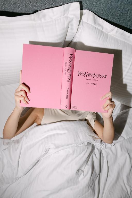 a person laying on a bed reading two books at AIRIO Athens Luxury Suites in Athens