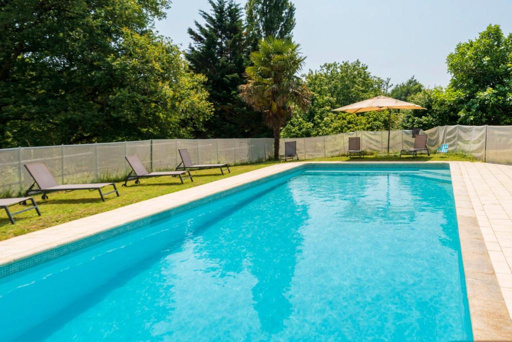 a swimming pool with chairs and an umbrella at La Caseta in Estang