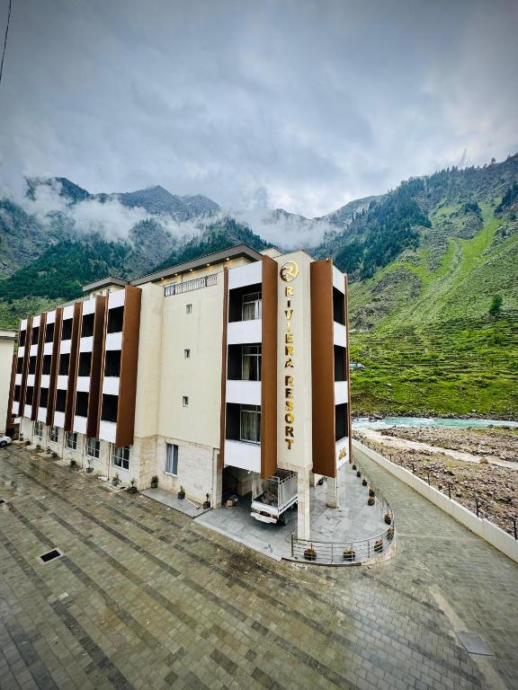 a large building in front of a mountain at Riviera Resort in Naran