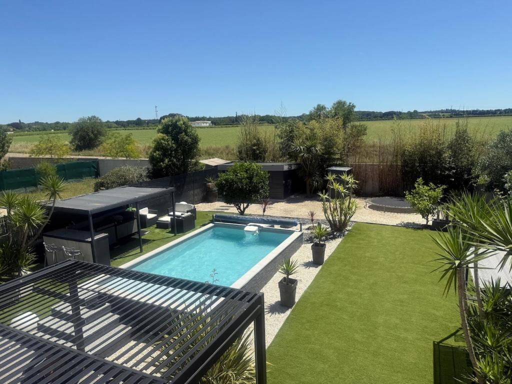 une arrière-cour avec une piscine et un jardin dans l'établissement Villa de standing avec piscine et climatisation, à Caissargues