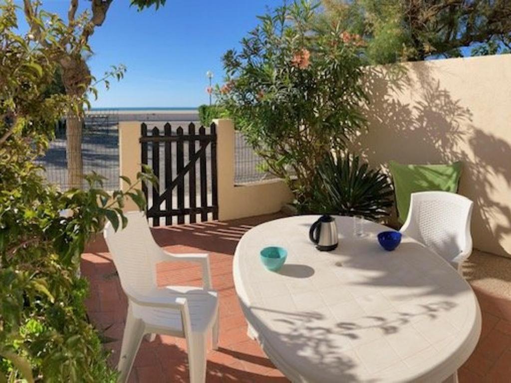 une table blanche et des chaises assises sur une terrasse dans l'établissement Appartement 3 pièces avec terrasse, calme, proche plage et commerces, 2 étoiles Meublé de Tourisme - FR-1-229D-214, à Saint Pierre La Mer