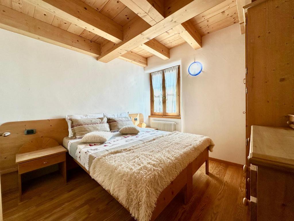 een slaapkamer met een bed in een kamer met houten plafonds bij Alpine Escape 6 in Bormio