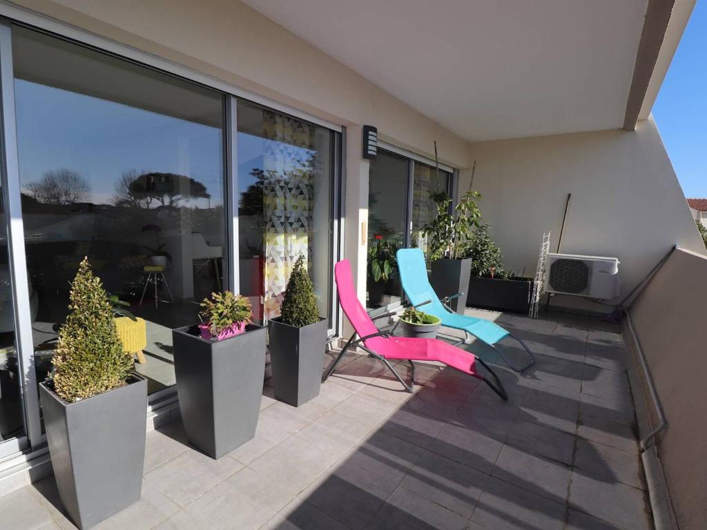 a patio with chairs and potted plants on a balcony at Luxueux P3 au Grau-du-Roi avec Terrasse et Parking Privé - FR-1-307-73 in Le Grau-du-Roi