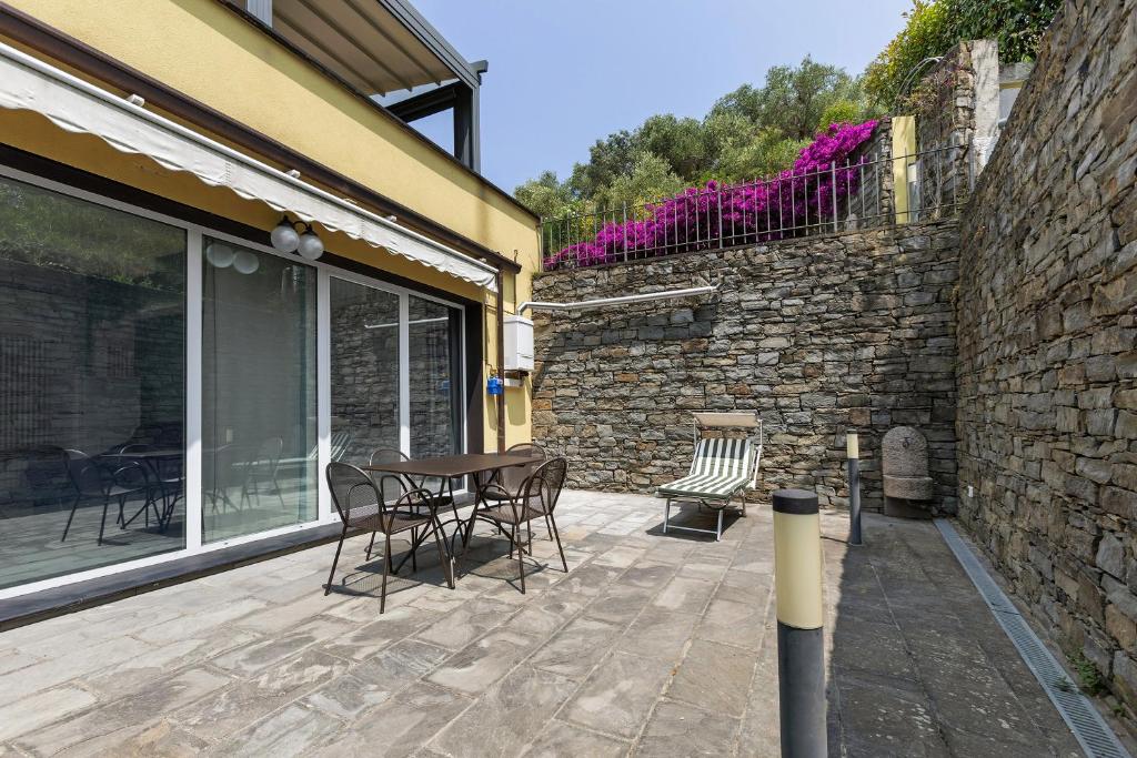 a patio with a table and chairs and a stone wall at Green House in Sestri Levante