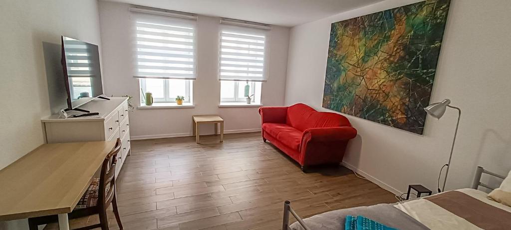 a living room with a red chair and a desk at Apartment 1 in Altstadt in Angermünde in Angermünde