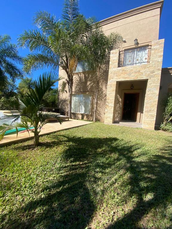 a house with a palm tree in front of it at Alojamiento la irene in Paso de la Patria