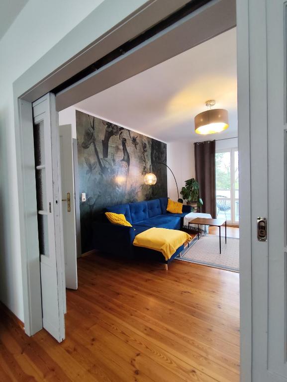 a living room with a blue couch and a painting at Calma Apartment in Weimar
