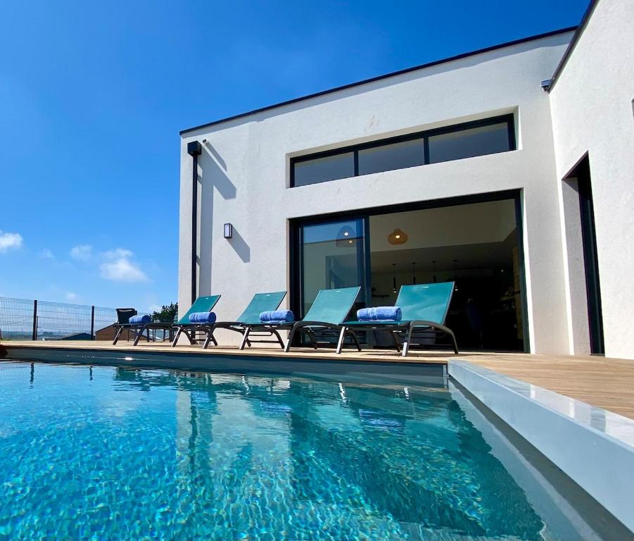 a house with a swimming pool with blue chairs at Escapade Marine piscine et spa pour 10 in Carantec
