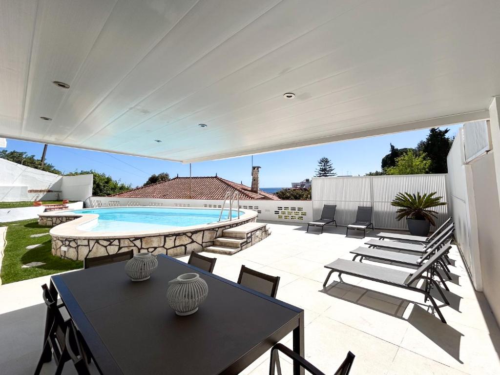 a patio with a table and chairs and a swimming pool at House T3 with Sea View and Private Pool - 5 minutes walk from the beach in Sesimbra