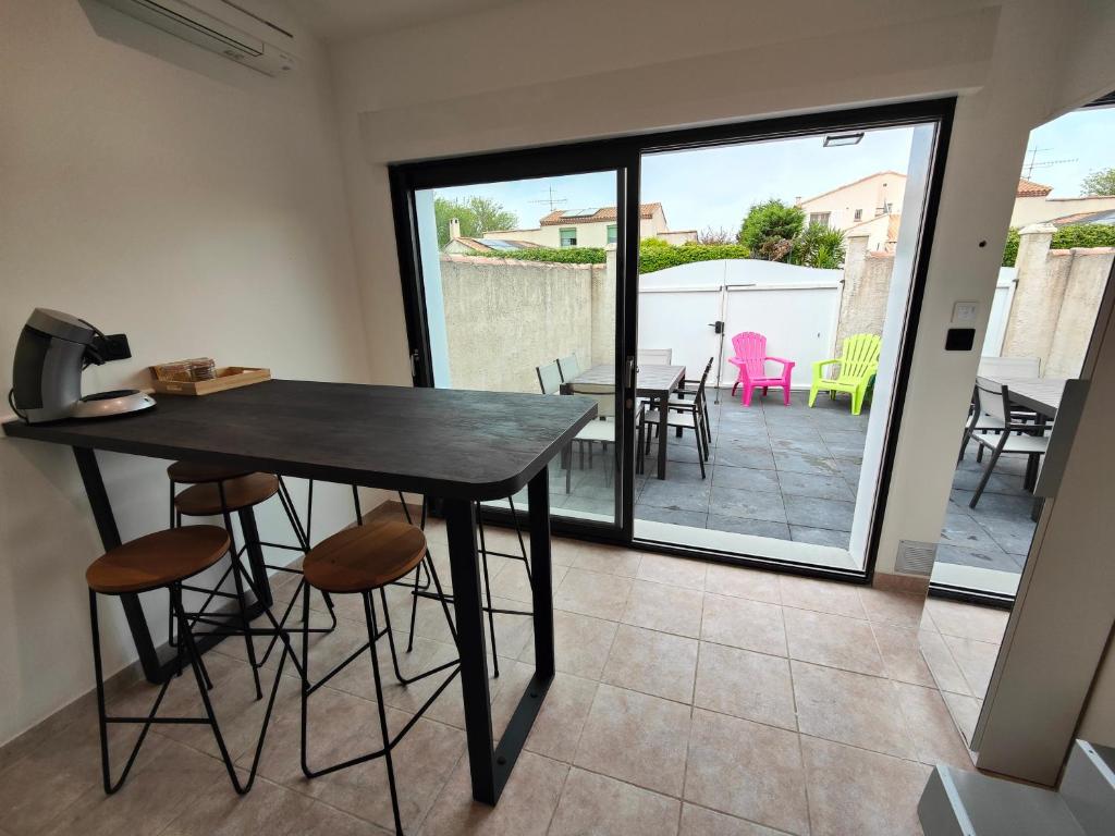 una sala da pranzo con tavolo e sedie e un patio di Maison classé 3 étoiles Pérols avec terrasse et clim a Pérols