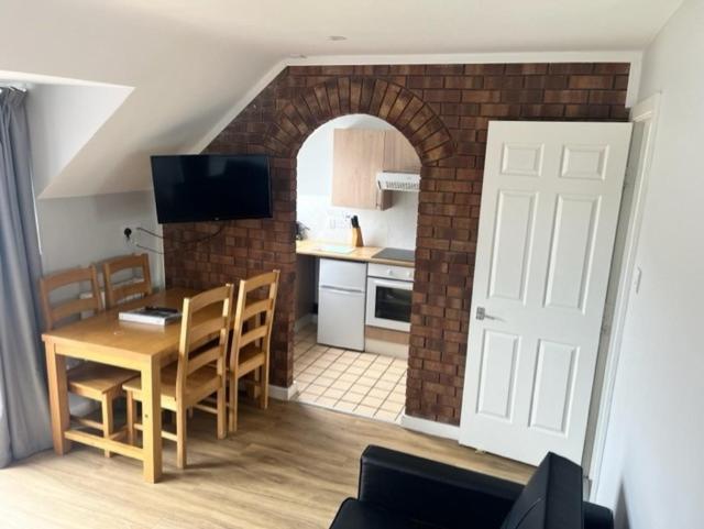 a kitchen with a dining table and a brick wall at Causeway Coast Apartment in Ballycastle