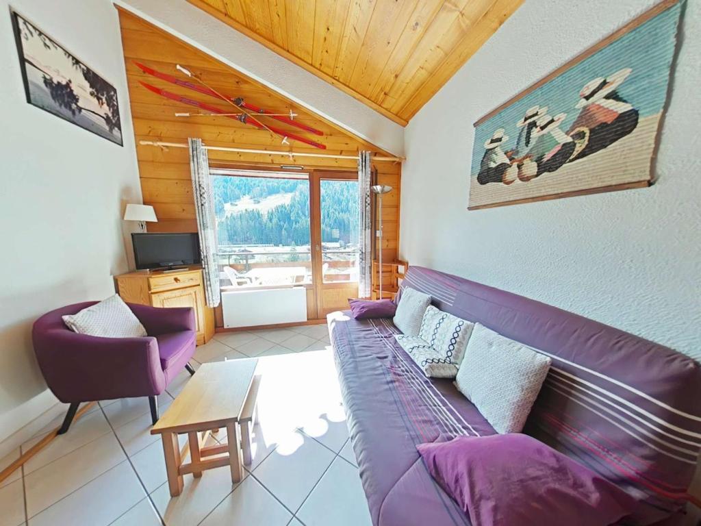 un salon avec un canapé violet et une table dans l'établissement Appt au centre avec 2 chambres, balcon, casier à ski et tout confort au Grand-Bornand - FR-1-241-61, au Grand-Bornand