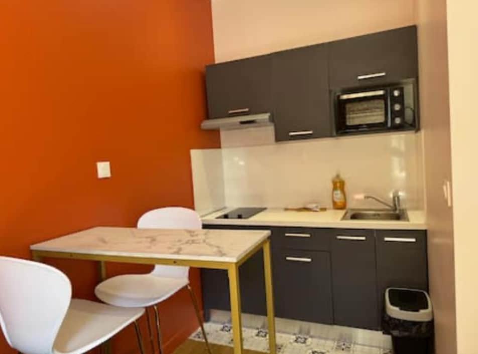 une petite cuisine avec une table et un micro-ondes dans l'établissement Charmant studio équipé, à Oullins
