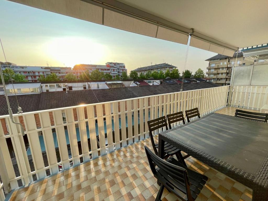 a deck with a table and chairs on a balcony at Apartment for six with shared pool in Porto Santa Margherita di Caorle