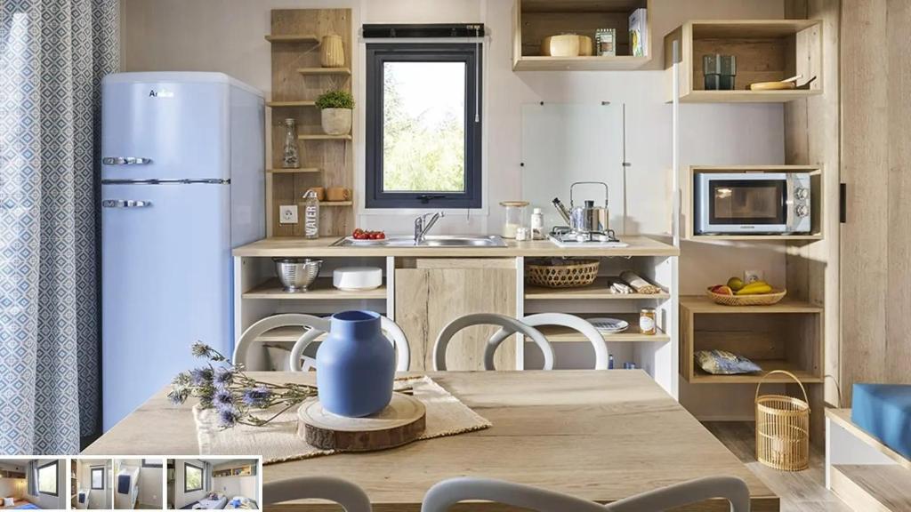 une cuisine avec une table et un réfrigérateur dans l'établissement Kokua Vacances présente MOBIL HOME résidentiel toutes options camping 3 étoiles LESCAR, à Lescar