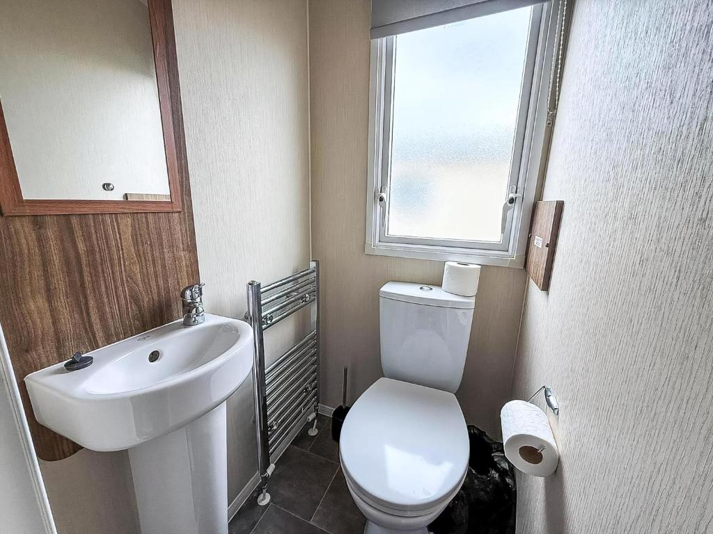 een badkamer met toilet, wastafel en raam bij Caravan In Scratby, Norfolk Ref 50071D in Great Yarmouth