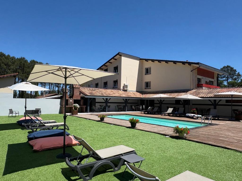 un complexe avec une piscine, des chaises et un parasol dans l'établissement Hôtel Paris Madrid, à Lesperon