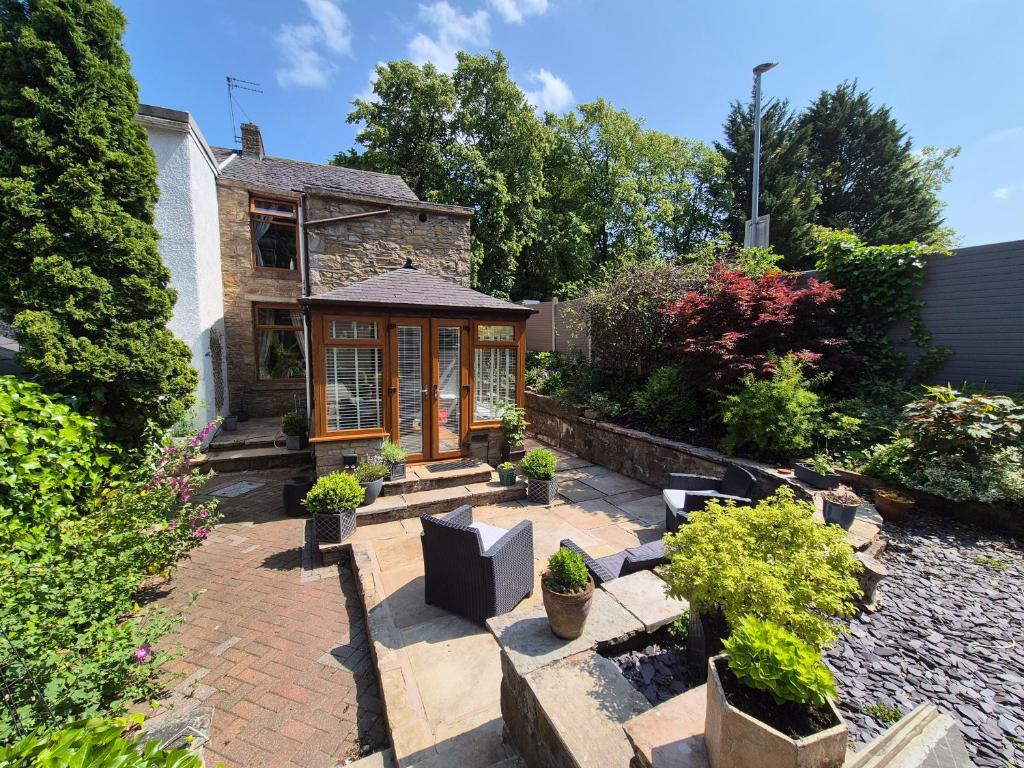 a garden with a brick patio and a house at Shore Cottage A traditional cosy cottage in Wilpshire