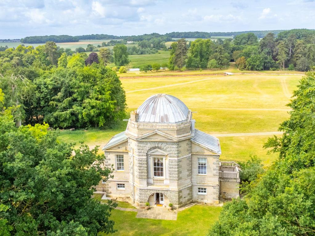 an old house in a field with trees at A Duke's Spectacular grand folly - The Temple in Euston