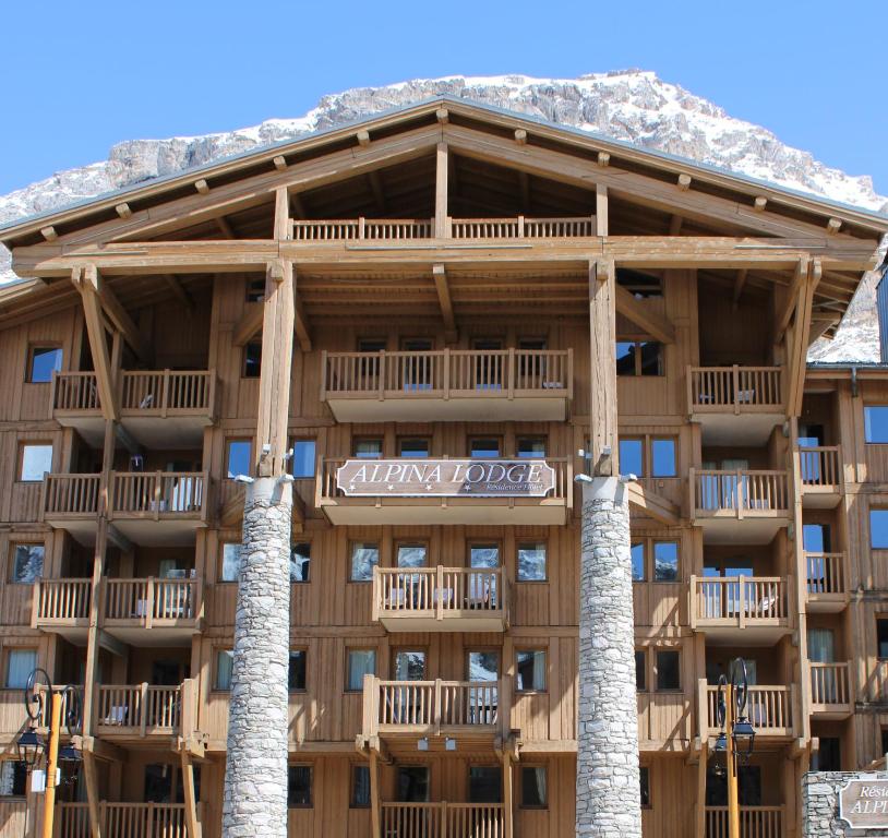 a large building with snow covered mountains in the background at Résidence Alpina Lodge in Val dʼIsère
