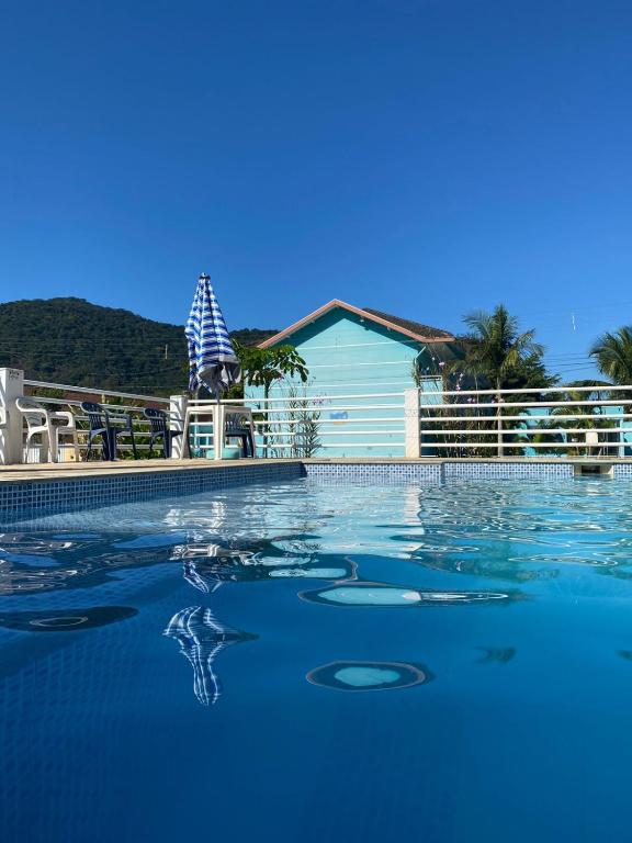 a swimming pool with blue water in front of a house at Chalés Céu e Mar Ubatuba in Ubatuba