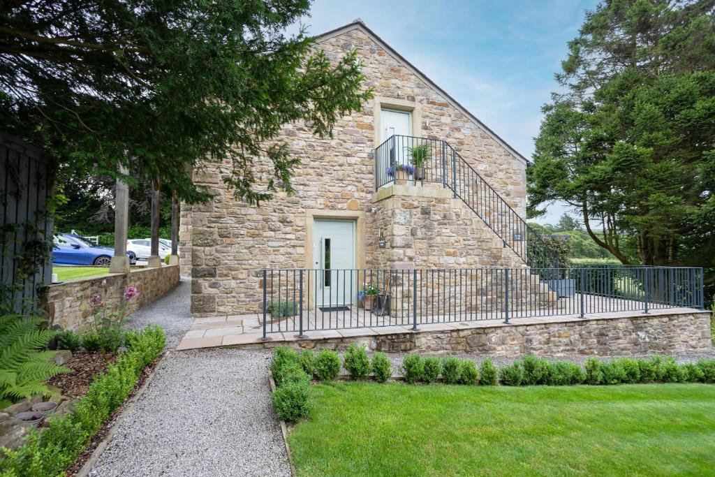 a stone house with a balcony and a yard at Bowland Lodges in Lancaster