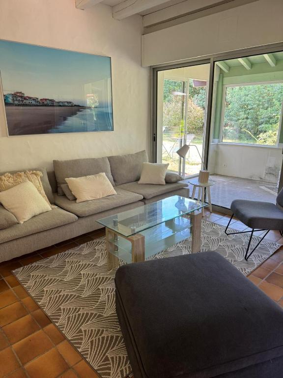 un salon avec un canapé et une table en verre dans l'établissement Villa Maeva spacieuse proche lac et océan, à Soorts-Hossegor