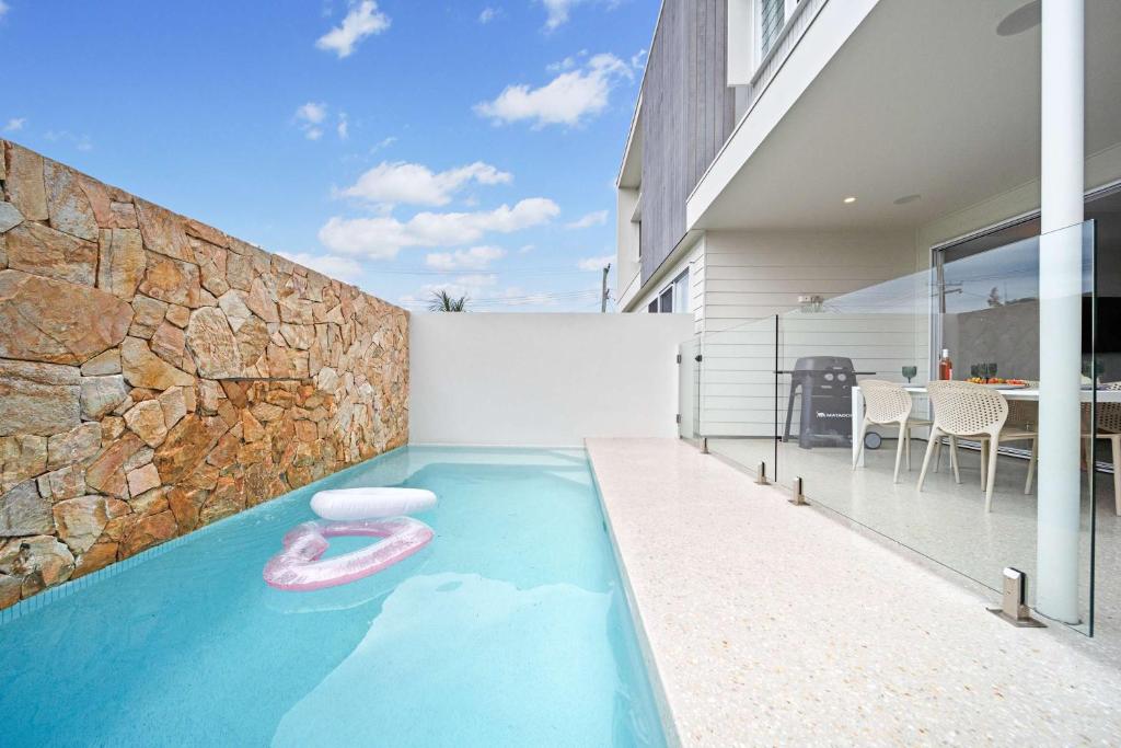 Bluebird Villa - 3min Stroll to Bokarina Beach في Bokarina: حمام سباحة مع عوامة وردية في المنزل