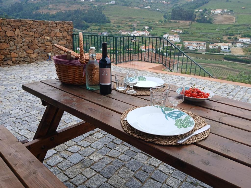 a picnic table with wine bottles and a basket of food at Quinta do Santo no Douro - Casa T2 in Alcarias
