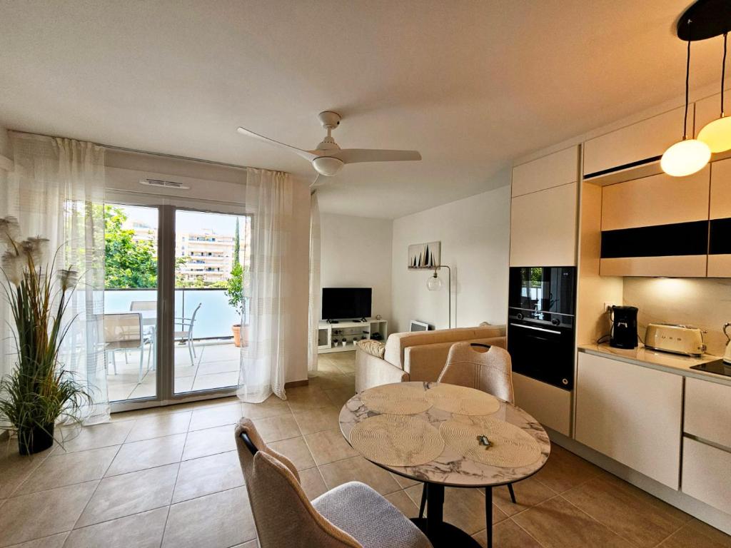 une cuisine et un salon avec une table et des chaises dans l'établissement Appartement neuf, 200m de la plage de Fréjus, à Fréjus