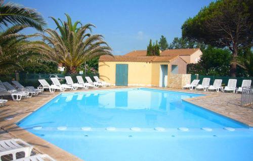 une grande piscine avec des chaises et une maison dans l'établissement Maisonnette 4places à marseillan plage., à Marseillan