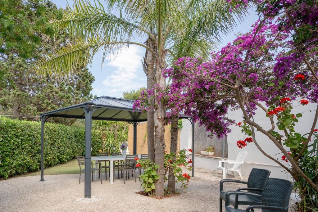 une terrasse avec une table, des chaises et des fleurs violettes dans l'établissement GuestHost - Casa Rosamarina Ostuni, à Rosa Marina