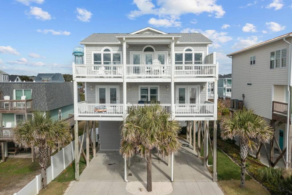 een wit huis met palmbomen ervoor bij Ocean View Pool Waterslide Elevator & Firepit in Oak Island