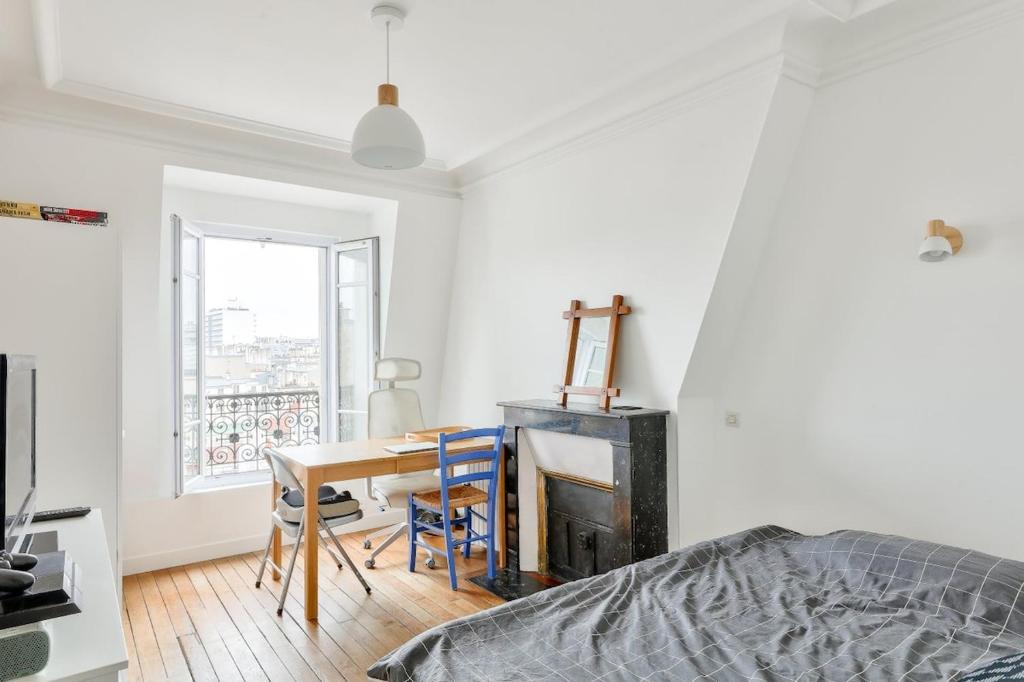 - une chambre avec un bureau et une table avec une chaise dans l'établissement Élégant studio près de la Place de la Bastille, à Paris