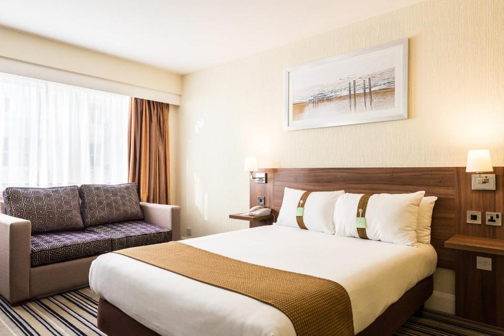 a hotel room with a bed and a chair at Holiday Inn Brighton Seafront by IHG in Brighton & Hove