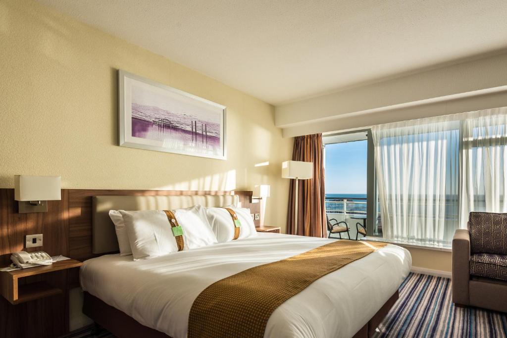 a hotel room with a large bed and a window at Holiday Inn Brighton Seafront by IHG in Brighton & Hove