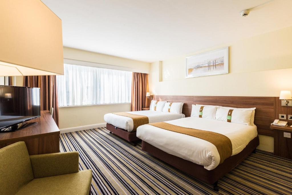 a hotel room with two beds and a television at Holiday Inn Brighton Seafront by IHG in Brighton & Hove