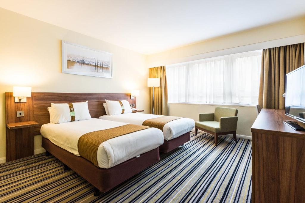 a hotel room with two beds and a flat screen tv at Holiday Inn Brighton Seafront by IHG in Brighton & Hove