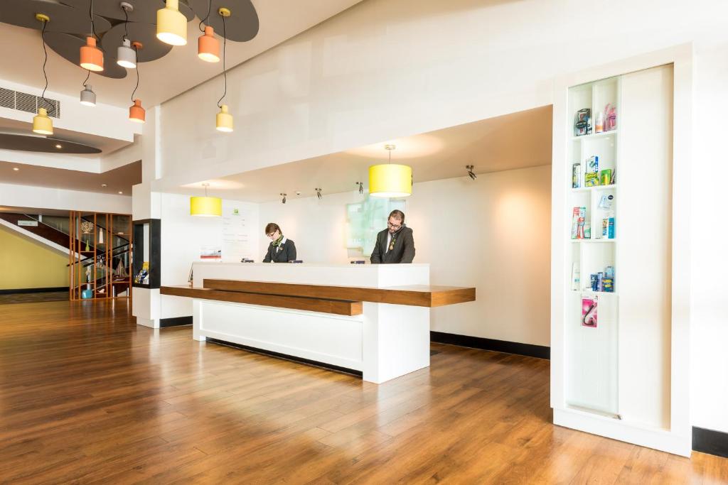 two people standing at a reception desk in a salon at Holiday Inn Brighton Seafront by IHG in Brighton & Hove