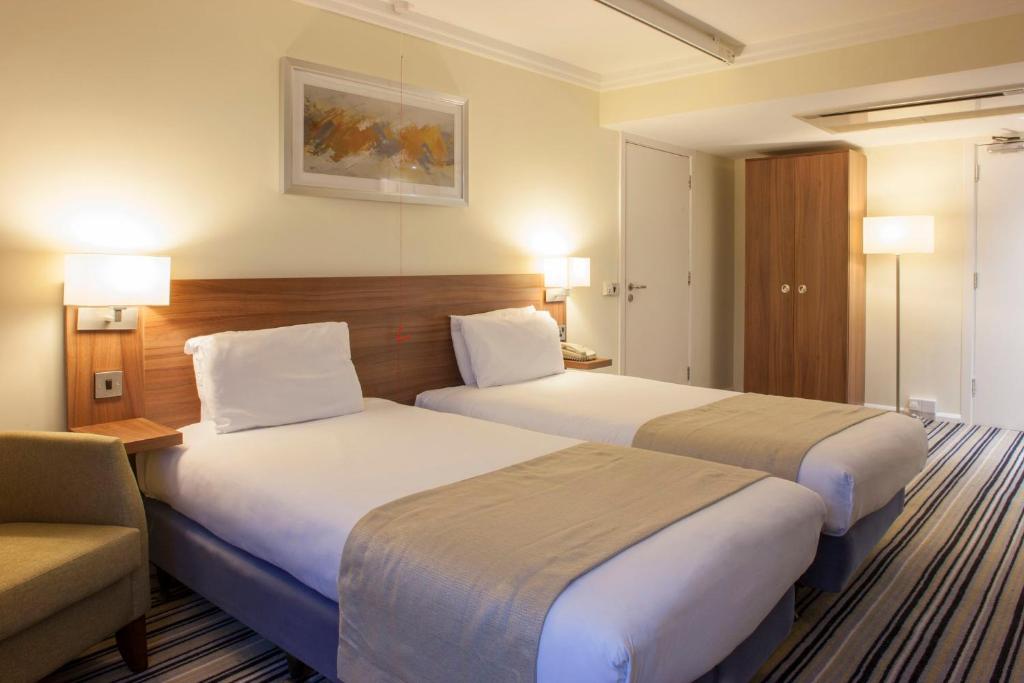 a hotel room with two beds and a couch at Holiday Inn Brighton Seafront by IHG in Brighton & Hove