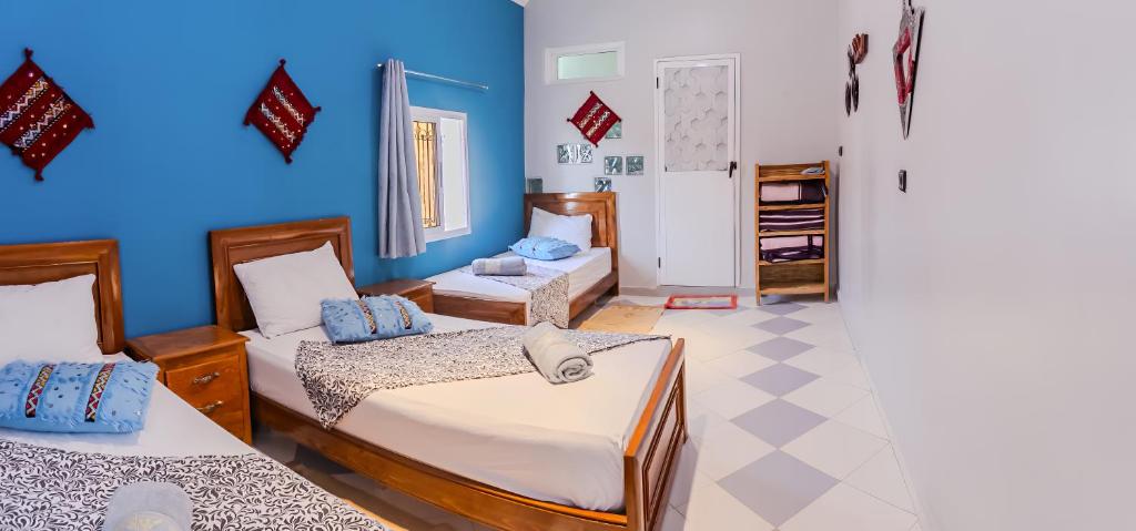 a bedroom with two beds and a blue wall at The Rina Hostel in Agadir