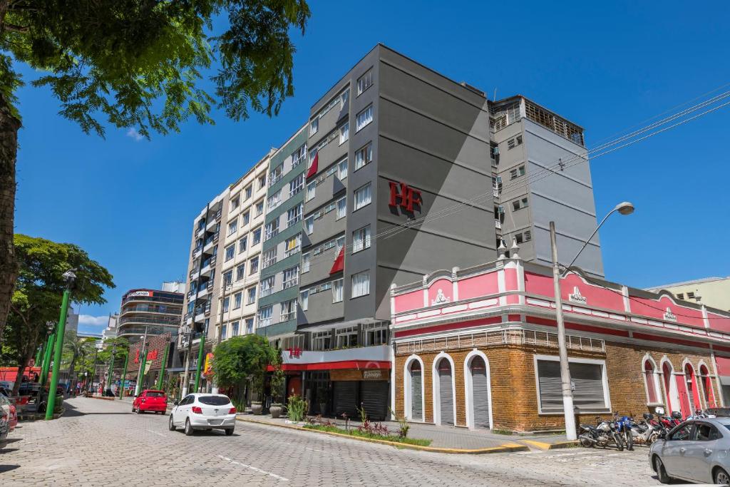 un edificio alto en una calle de la ciudad con coches en Hotel Fabris, en Nova Friburgo