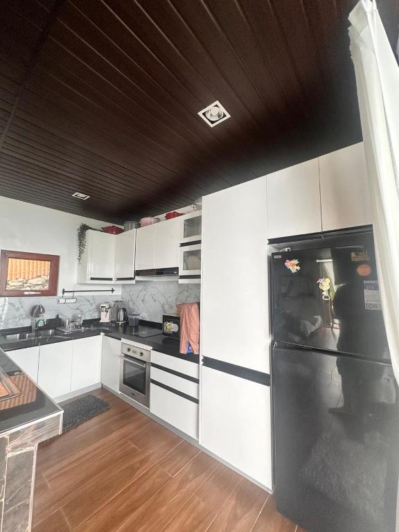 a kitchen with white cabinets and a black refrigerator at Barney's Pointe Beach House, Batangas City in Batangas City