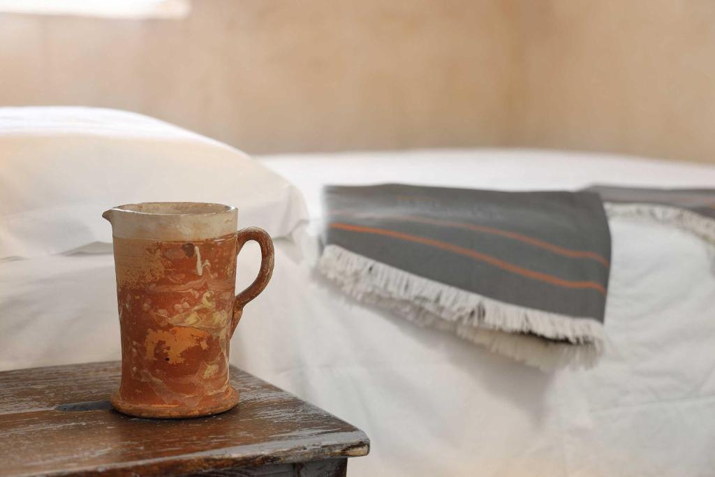 a coffee cup sitting on a table next to a bed at Masseria Borgo Sentinella in Torre dell'Orso