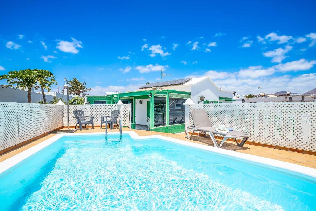 a swimming pool with two chairs and a house at Casa Sussa in Tías