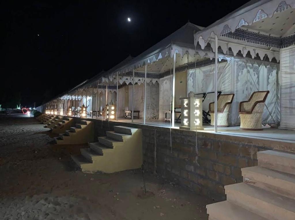 a building with chairs and lights at night at Hostel Desert Camp Sam in Jaisalmer