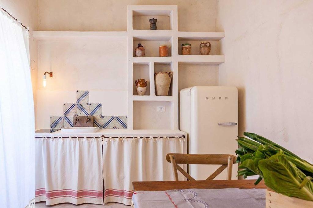 a kitchen with a table and a refrigerator at Masseria Borgo Sentinella in Torre dell'Orso