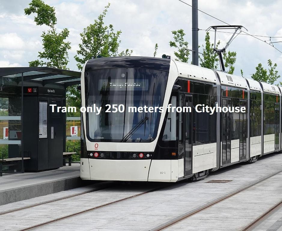 a tram only meters from cityulse is stopped at a train station at City House in Odense